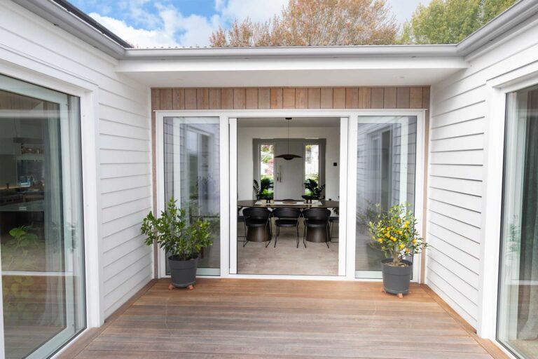 Exterior courtyard view looking through the wide glazed doors into the dining area.