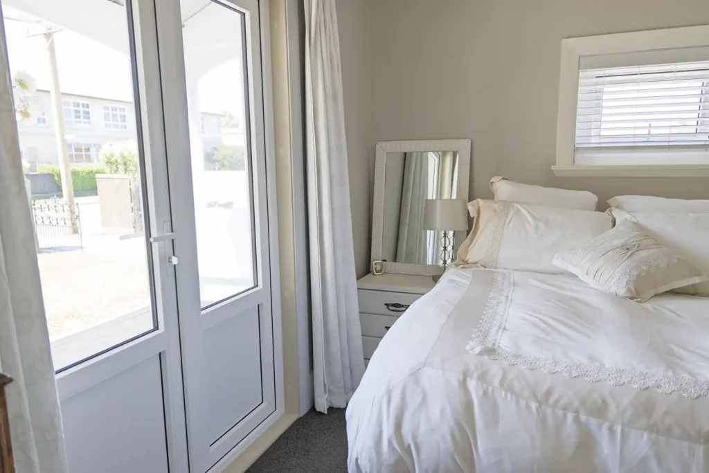 bedroom with uPVC double glazed French doors opening to veranda Christchurch villa